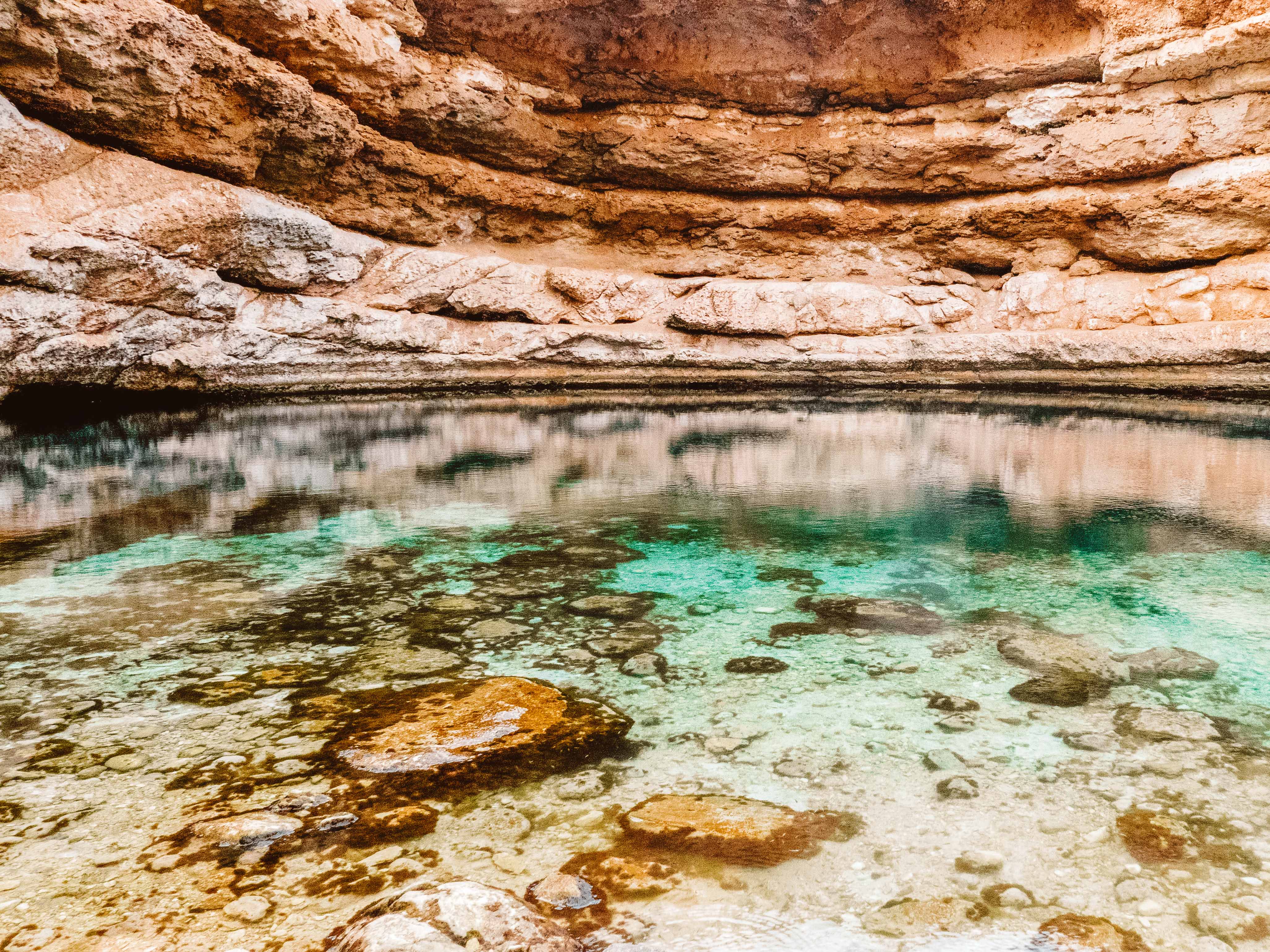 Green water surrounded by rocky walls at Bimmah Sinkhole