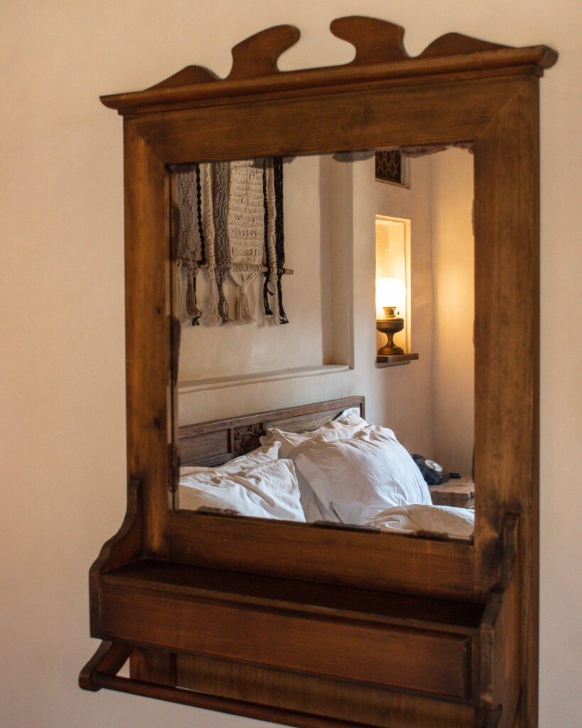 Reflection of white pillows on a a bed in a wooden framed mirror at Al Seef Heritage Hotel, Dubai