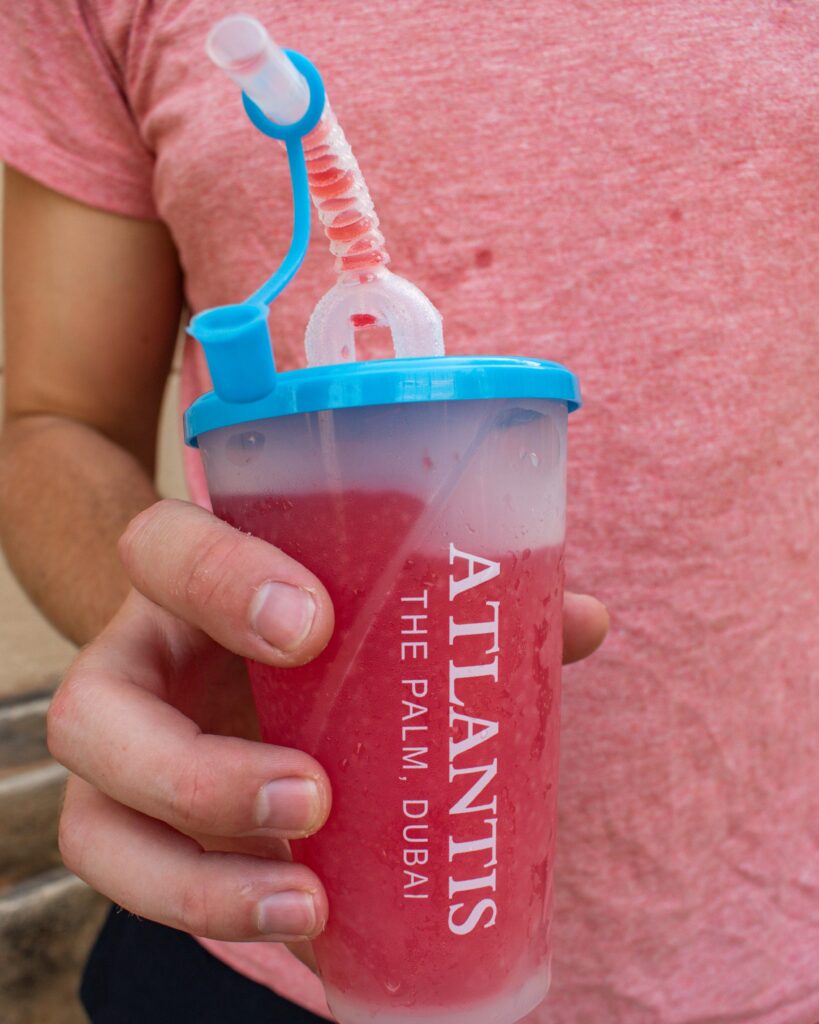 Man's hand holding branded Atlantis, The Palm, drink